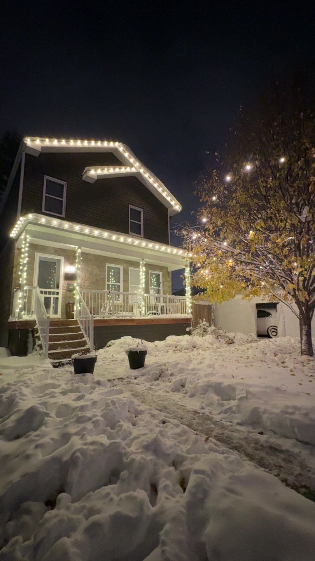 Maison illuminée pour les Fêtes à Montréal — ligne de toit, galerie et colonnes enrubannées, sous la neige